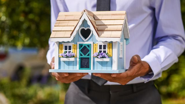 a%20person%20holding%20a%20wooden%20house%20model